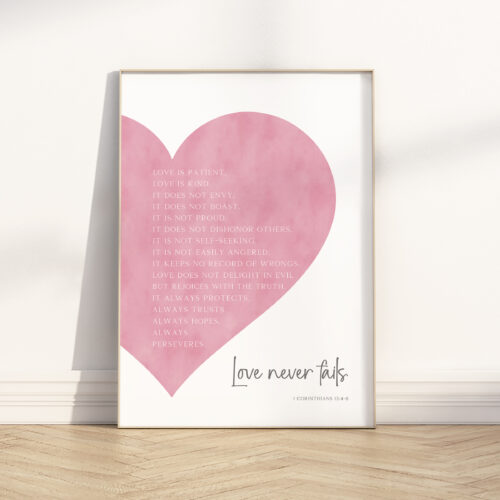 Love never fails wall art featuring 1 Corinthians 13:4–8 Bible verse in a pink watercolor heart, Christian scripture home decor print